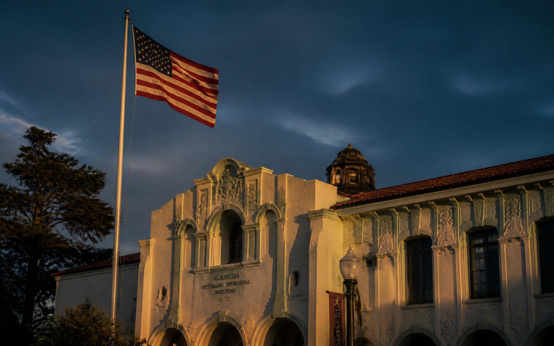 American flag over the Alameda Veterans Memorial Building at dusk